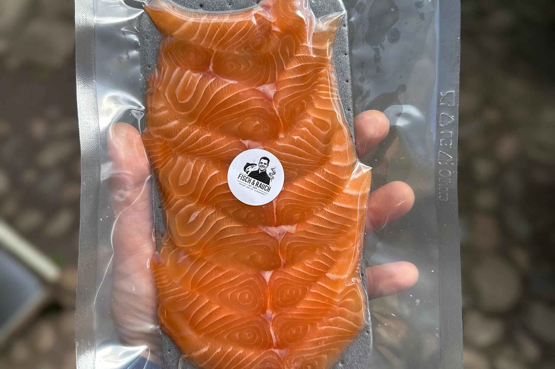 eine Hand die geräucherten Fisch hält